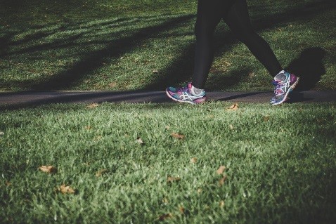 Person walking down a path in athletic shoes.