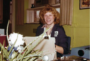 Lynn Sullivan in the 1970s at her desk, wearing the required blue smock.